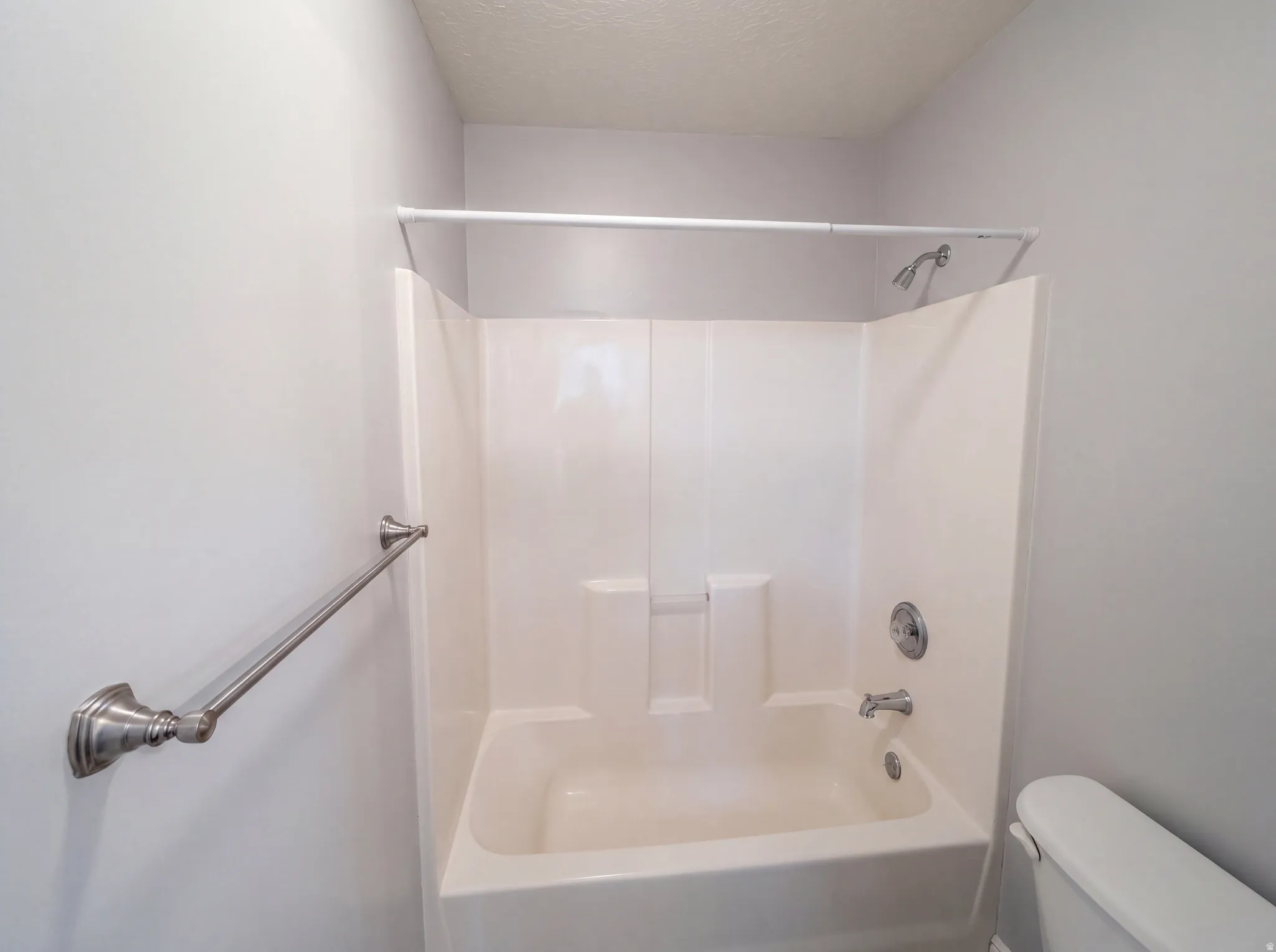 Bathroom with a textured ceiling and shower / bathtub combination