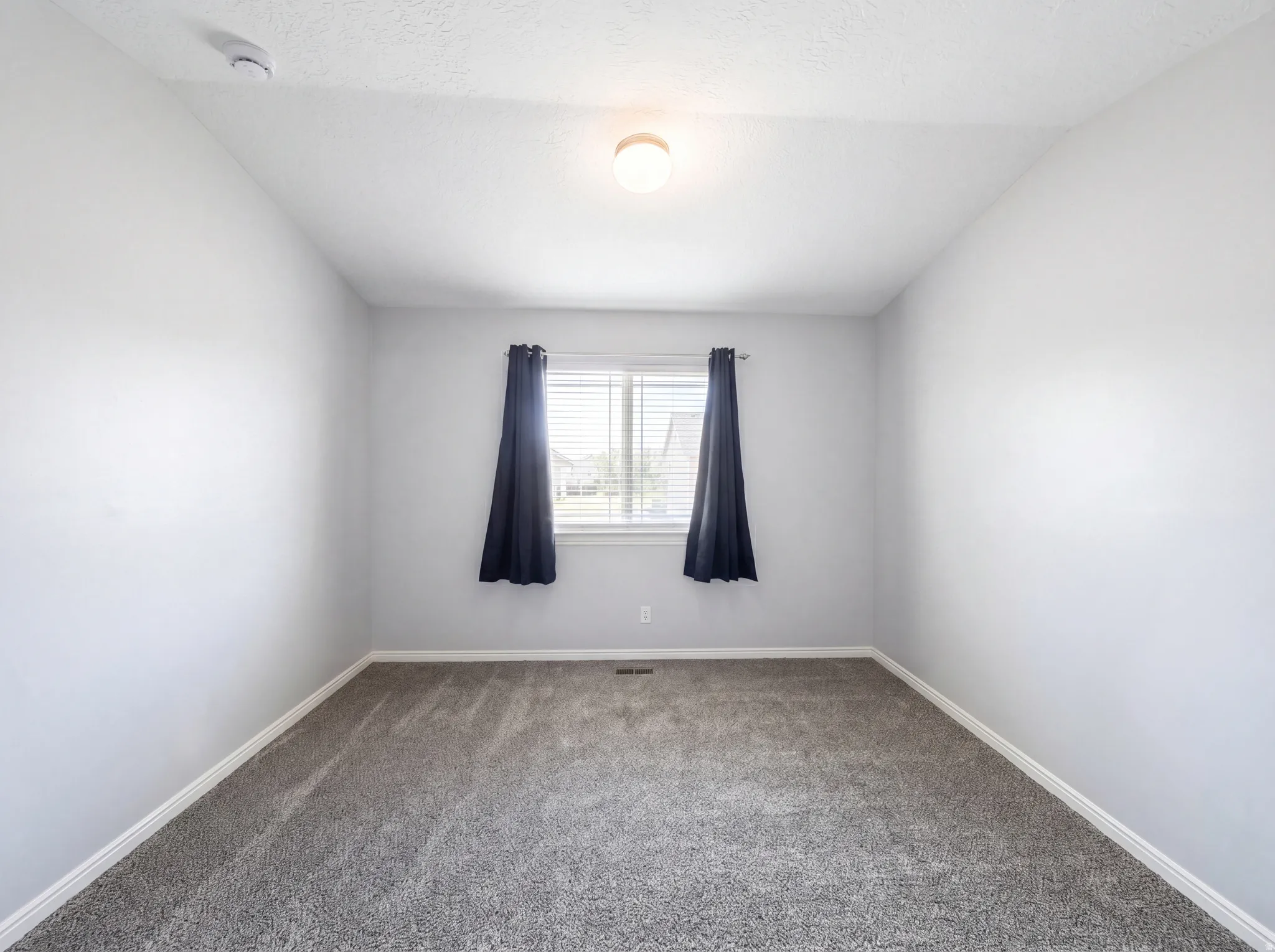 Unfurnished room with carpet floors, a textured ceiling, and a smoke detector
