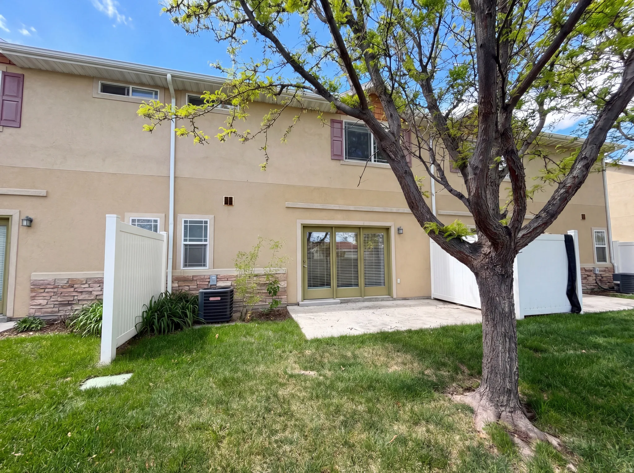 Back of property featuring stucco siding, a lawn, a patio, and stone siding