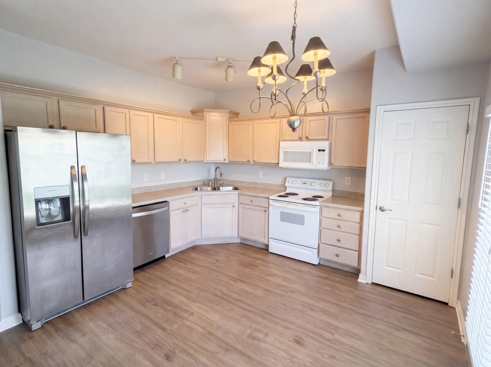 Kitchen featuring stainless steel appliances, hanging lights, light countertops, light wood-type flooring, and light wood finish cabinets