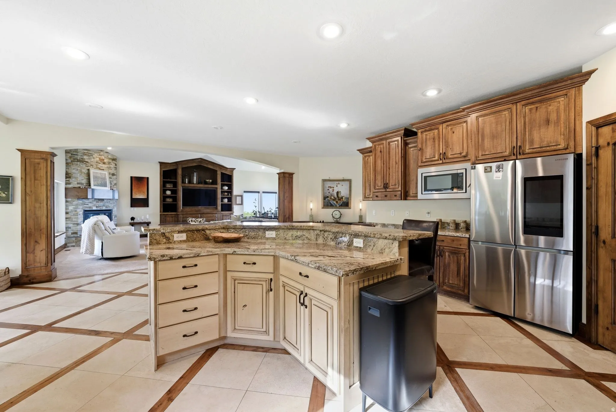 Kitchen featuring stainless steel appliances, inlaid floor details, open floor plan, a fireplace, and a kitchen island