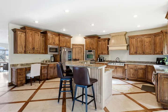 Kitchen featuring inlaid floor details, a kitchen bar, wood finish cabinetry, stainless steel appliances, and recessed lighting