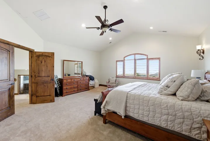 Primary bedroom featuring lofted ceiling, light colored carpet, a ceiling fan, and recessed lighting