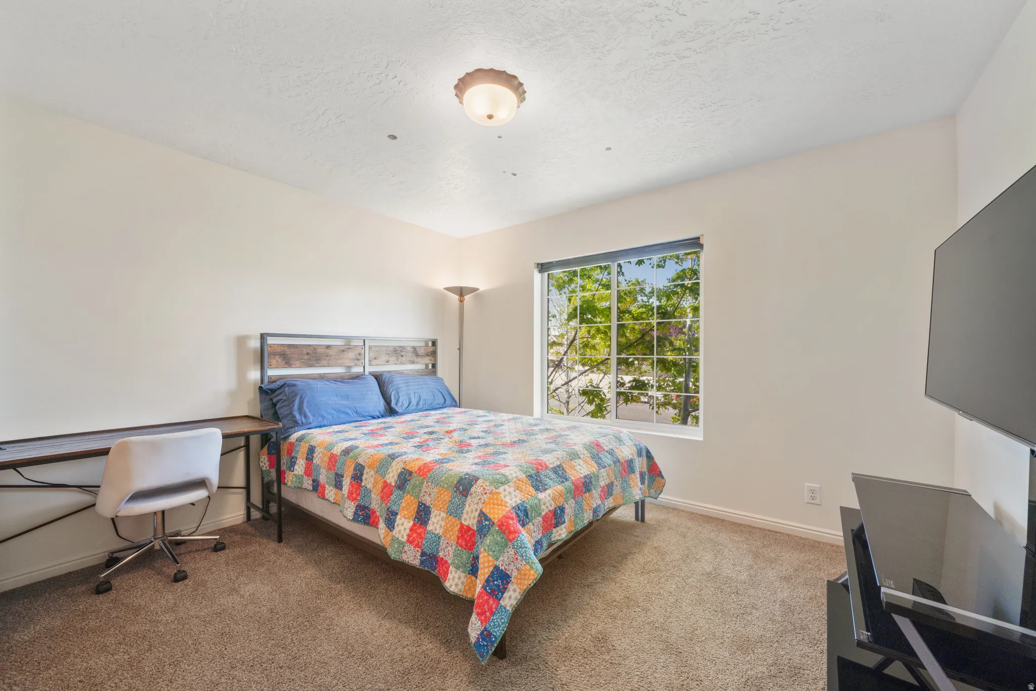 Bedroom featuring light colored carpet and a textured ceiling
