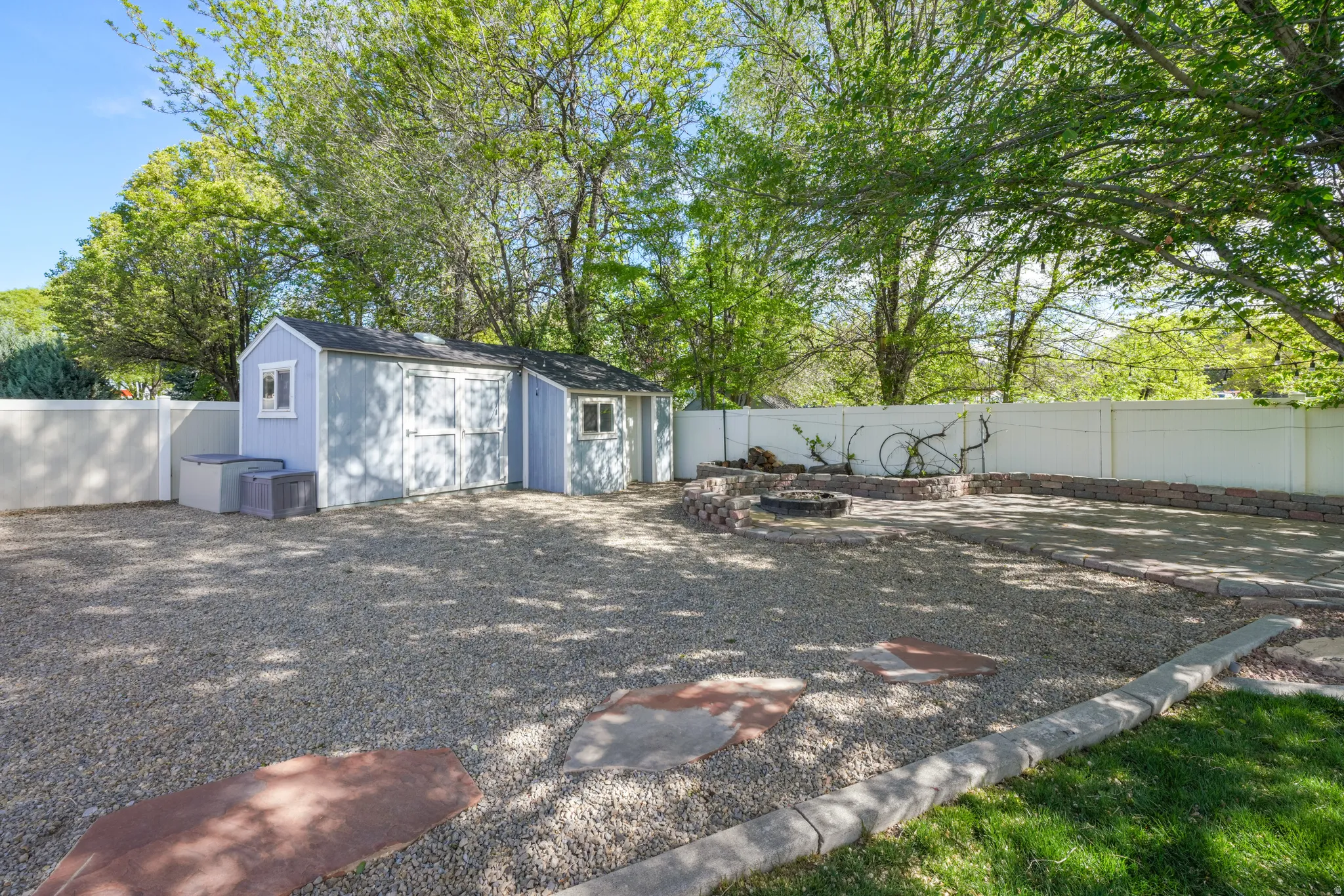 Fenced backyard with an outdoor fire pit and a storage shed