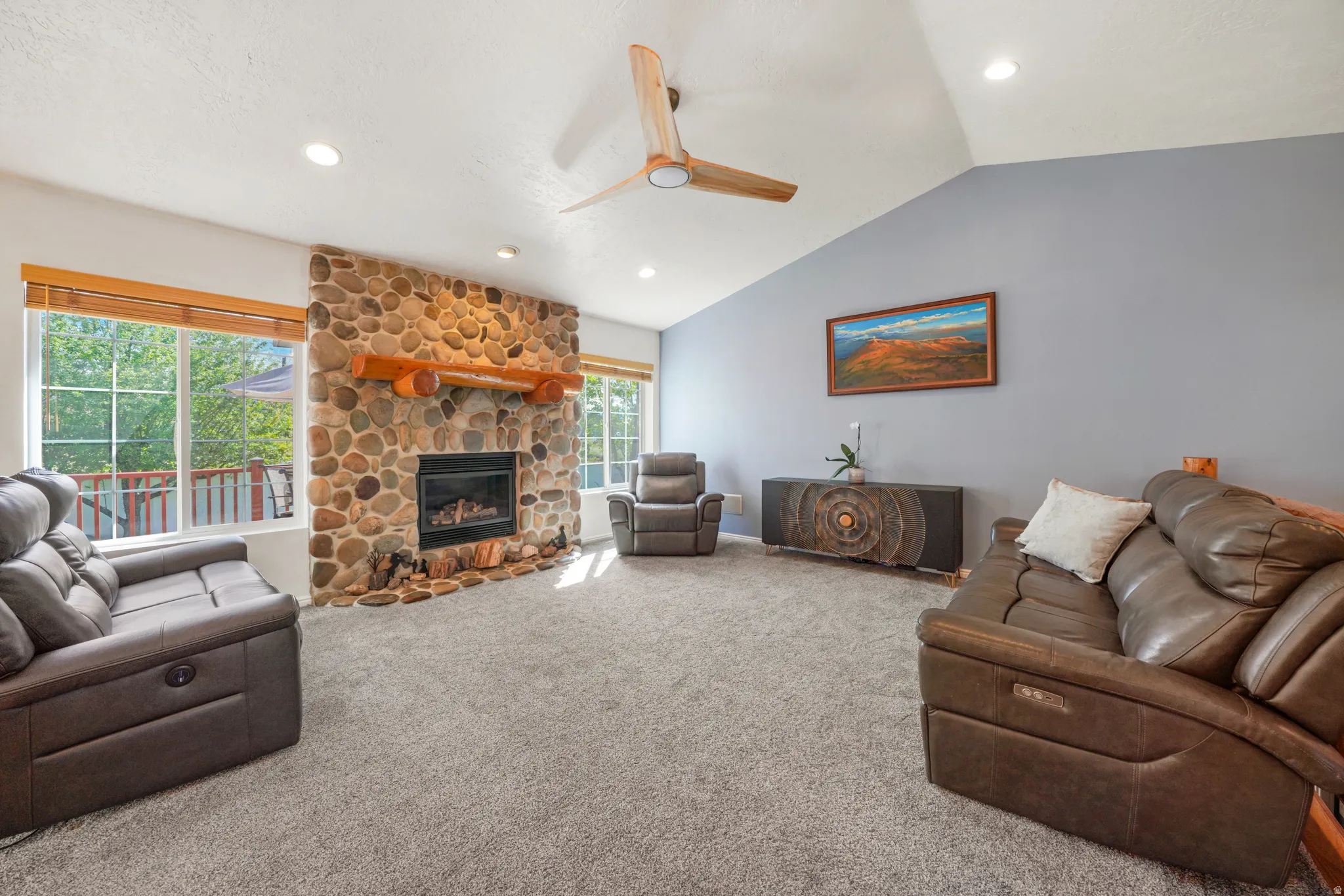 Living room featuring ceiling fan, carpet flooring, a stone fireplace, lofted ceiling, and recessed lighting
