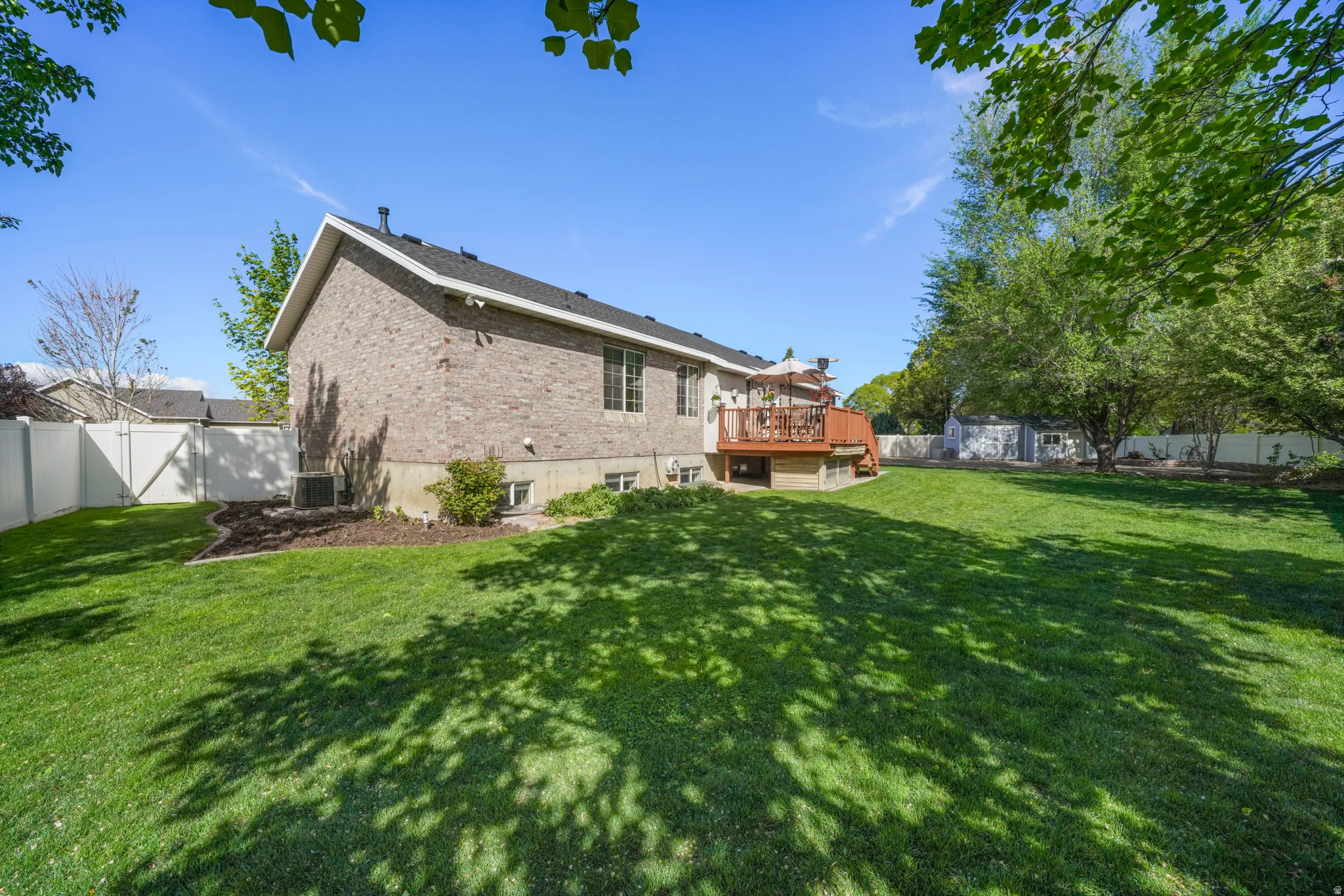 Rear view of property featuring a deck, brick siding, and a fenced backyard