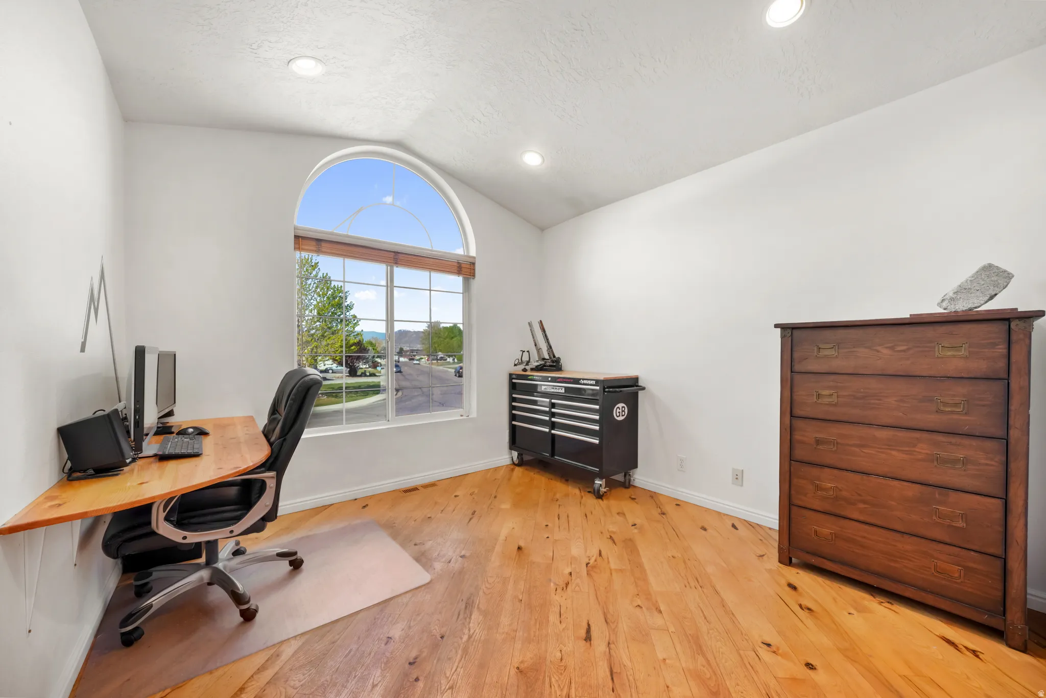 Office area featuring vaulted ceiling, light wood finished floors, and recessed lighting