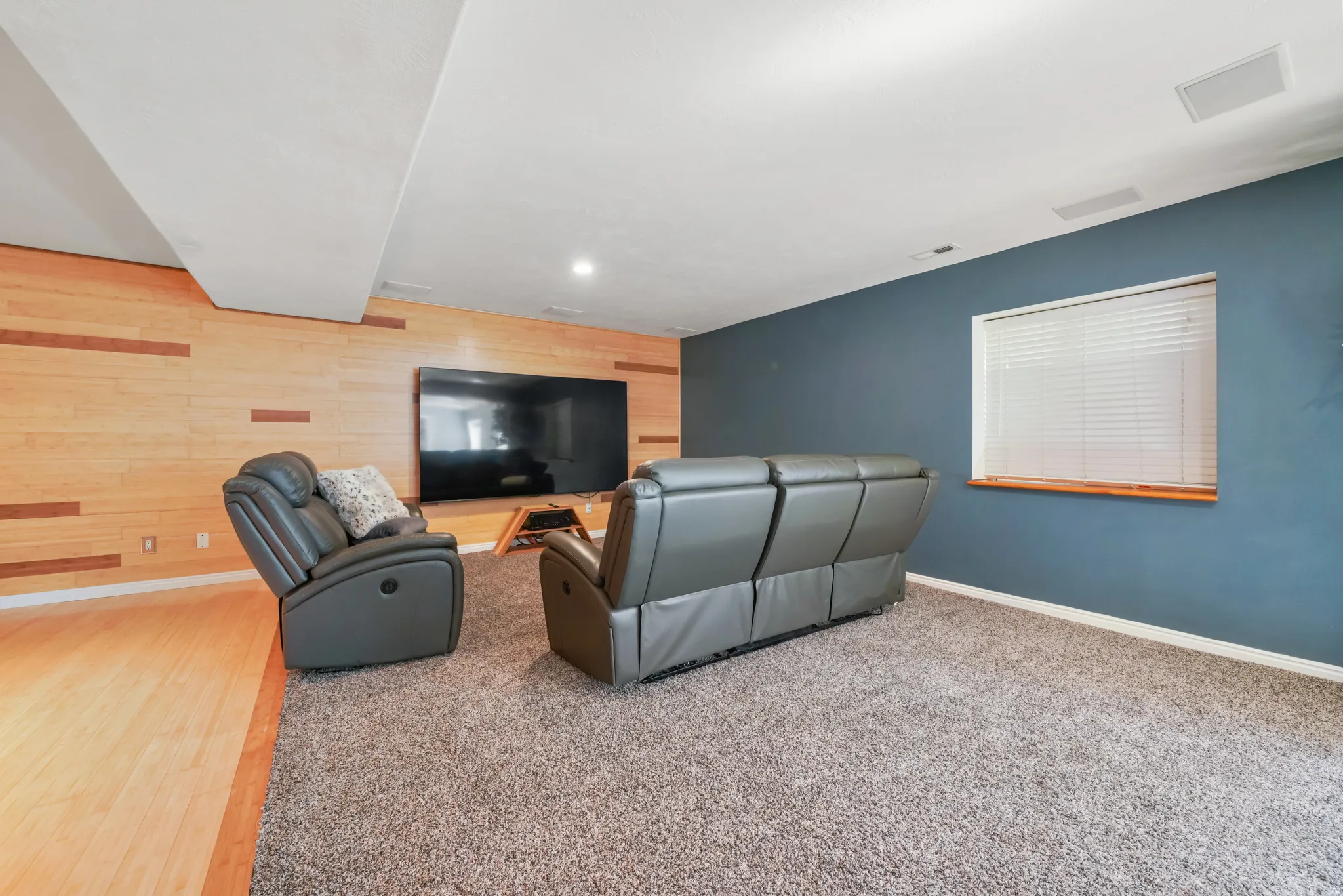 Living area with wood walls, an accent wall, recessed lighting, and light colored carpet