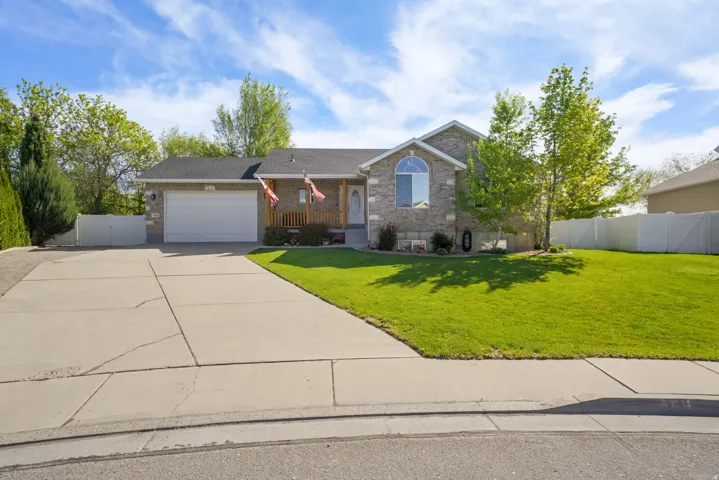 Single story home featuring brick siding, concrete driveway, an attached garage, and a porch