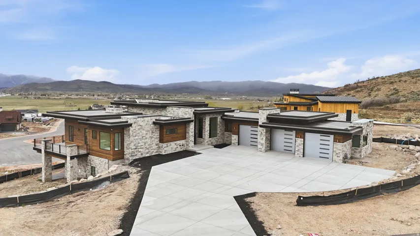 Contemporary home with a mountain view, stone siding, driveway, and a garage