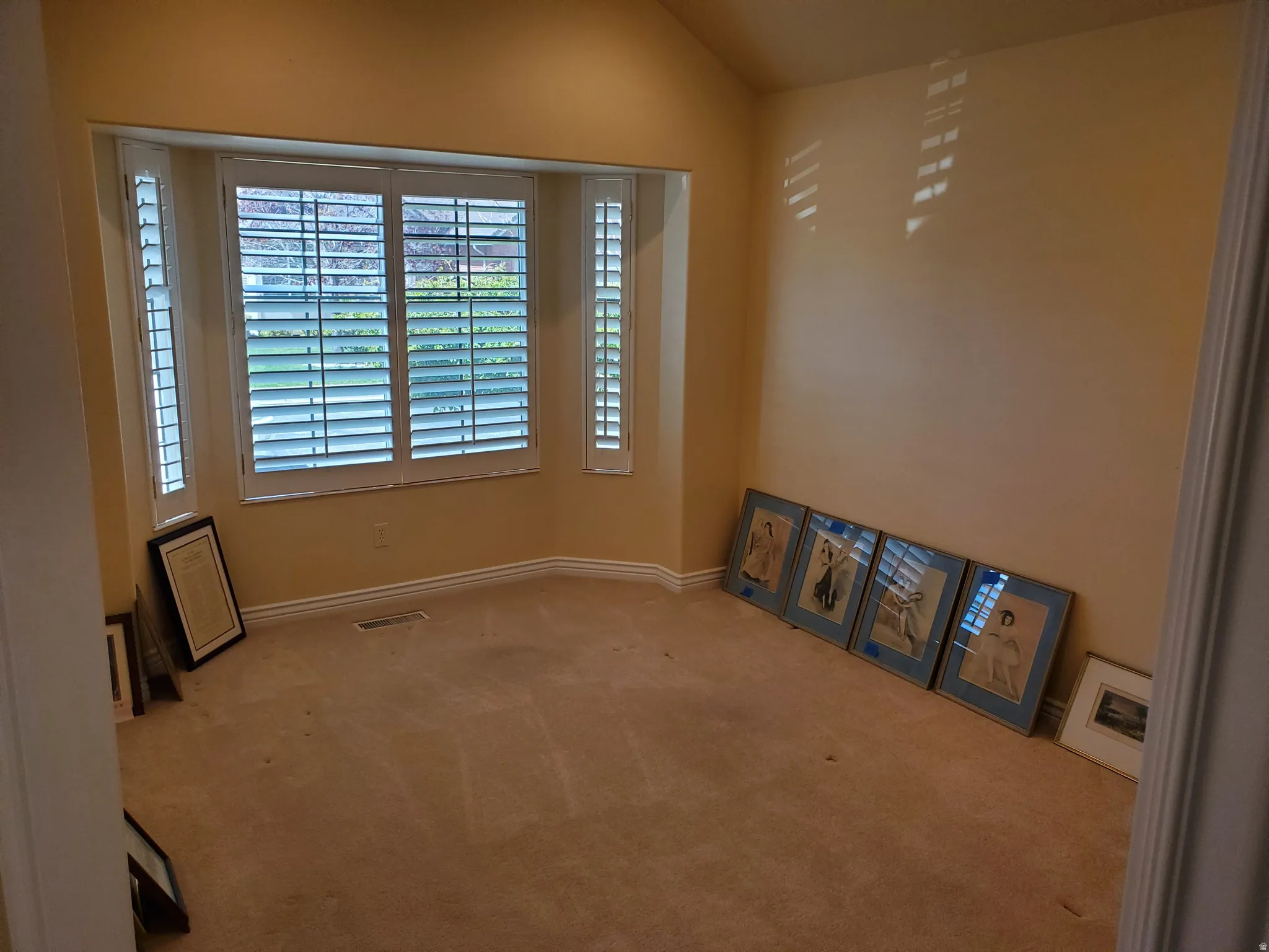 Spare room featuring light colored carpet and vaulted ceiling