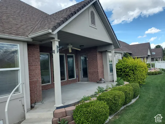 Rear view of property with brick siding, a ceiling fan, roof with shingles, and stucco siding