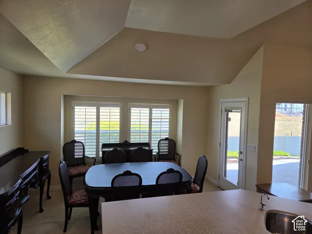 Vaulted ceiling design, white plantation shutters, glass-paneled exterior door, and a built-in sink with a gooseneck faucet