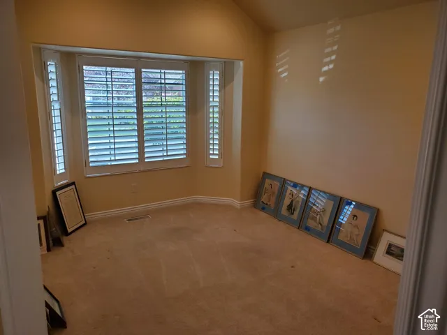 Spare room featuring light colored carpet and vaulted ceiling