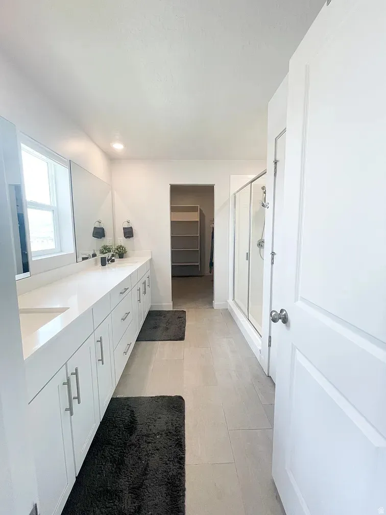 Bathroom featuring a stall shower, double vanity, a walk in closet, and recessed lighting