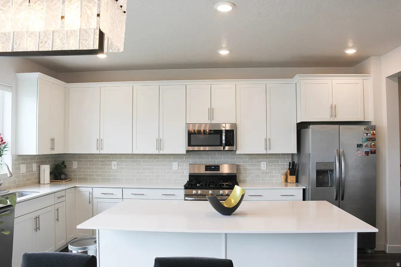 Kitchen with a kitchen breakfast bar, stainless steel appliances, a center island, recessed lighting, and white cabinetry