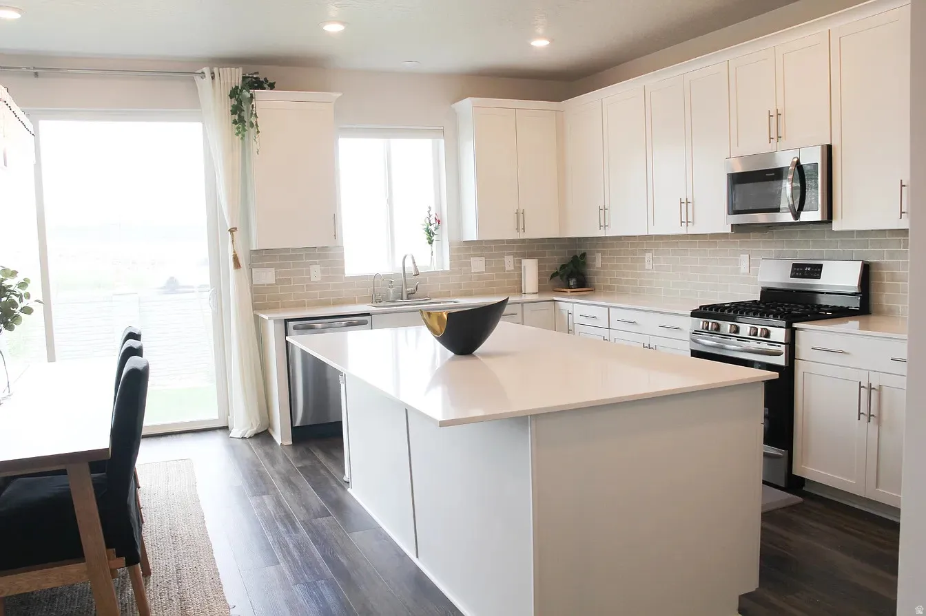 Kitchen featuring stainless steel appliances, white cabinetry, dark wood-style floors, a center island, and recessed lighting