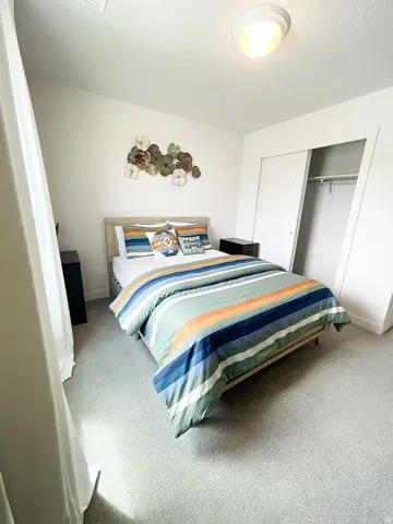 Bedroom with carpet, a closet, and a textured ceiling