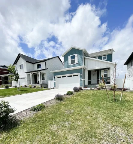 Modern farmhouse featuring covered porch, a garage, driveway, and board and batten siding