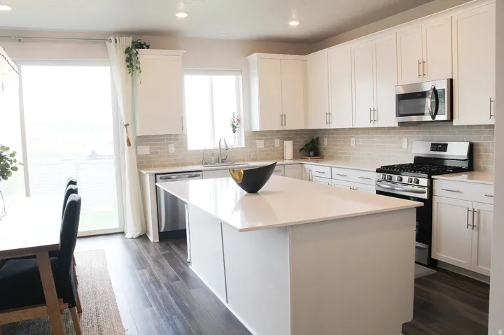 Kitchen featuring stainless steel appliances, white cabinetry, dark wood-style floors, a center island, and recessed lighting