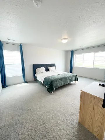 Bedroom featuring a textured ceiling and light carpet