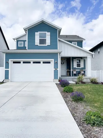 View of front facade featuring a porch, driveway, an attached garage, and board and batten siding