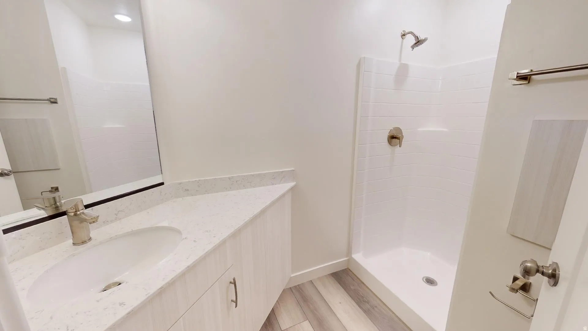 Full bathroom featuring a shower stall, vanity, and light wood-type flooring