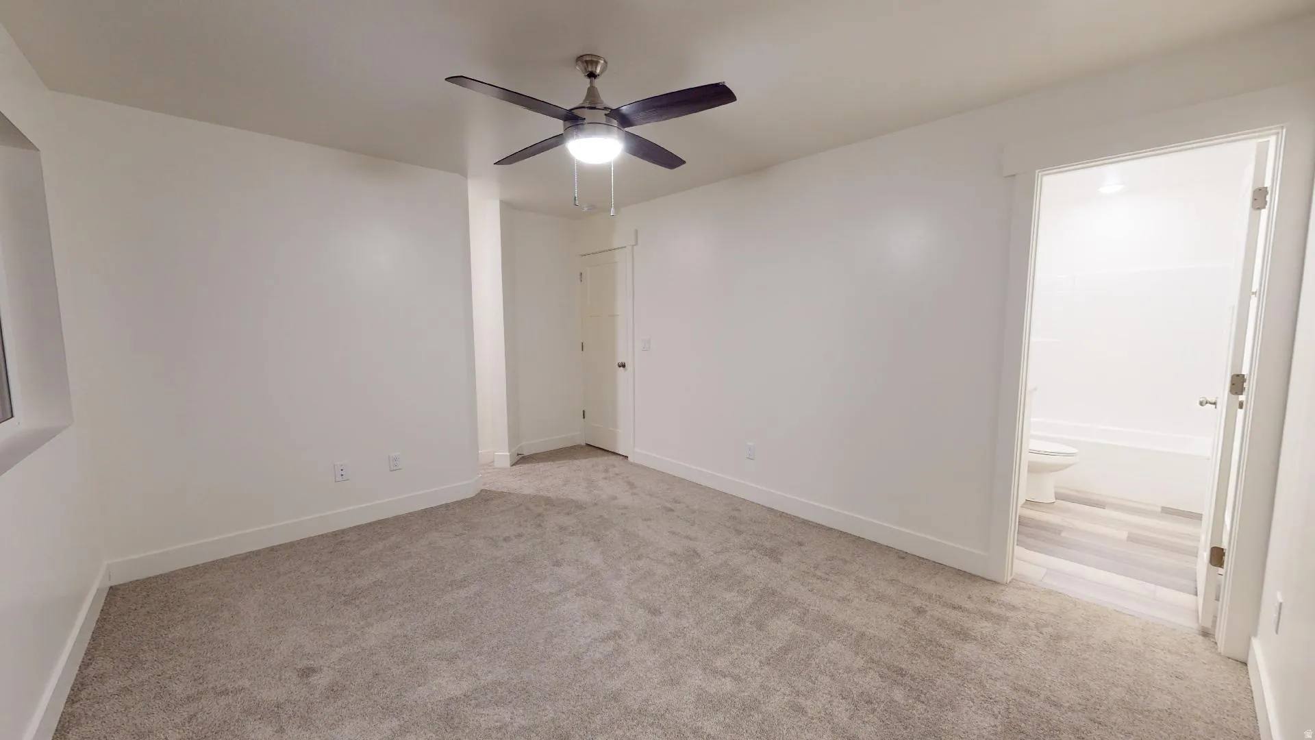Unfurnished bedroom featuring light colored carpet, ceiling fan, and connected bathroom