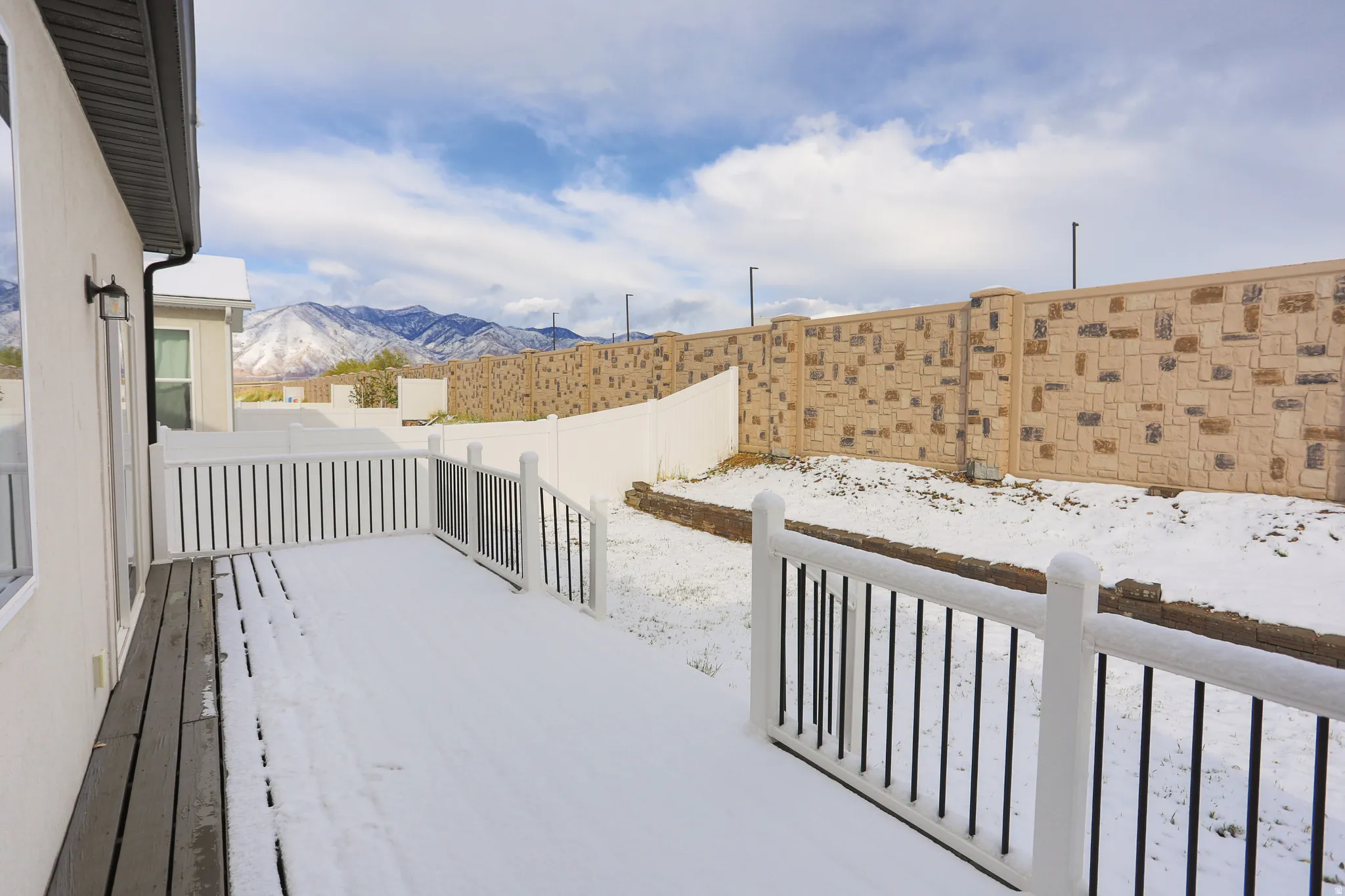 Yard covered in snow featuring a deck with mountain view and a fenced backyard