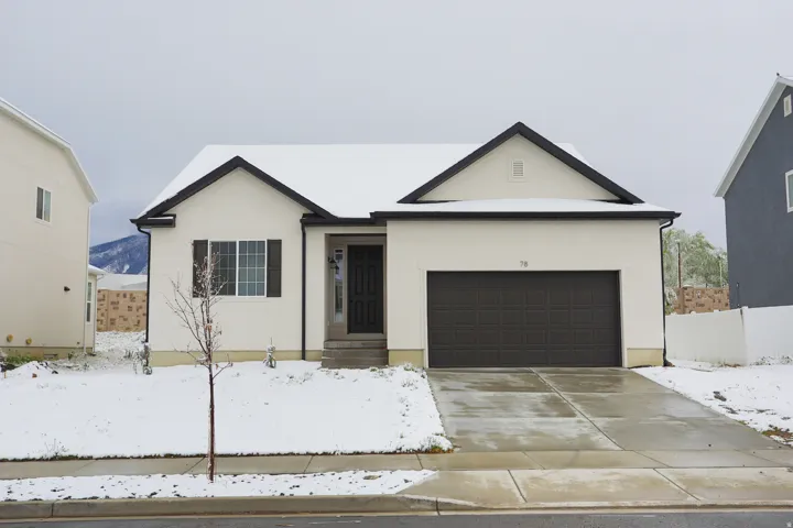 View of front facade featuring driveway, an attached garage, and stucco siding