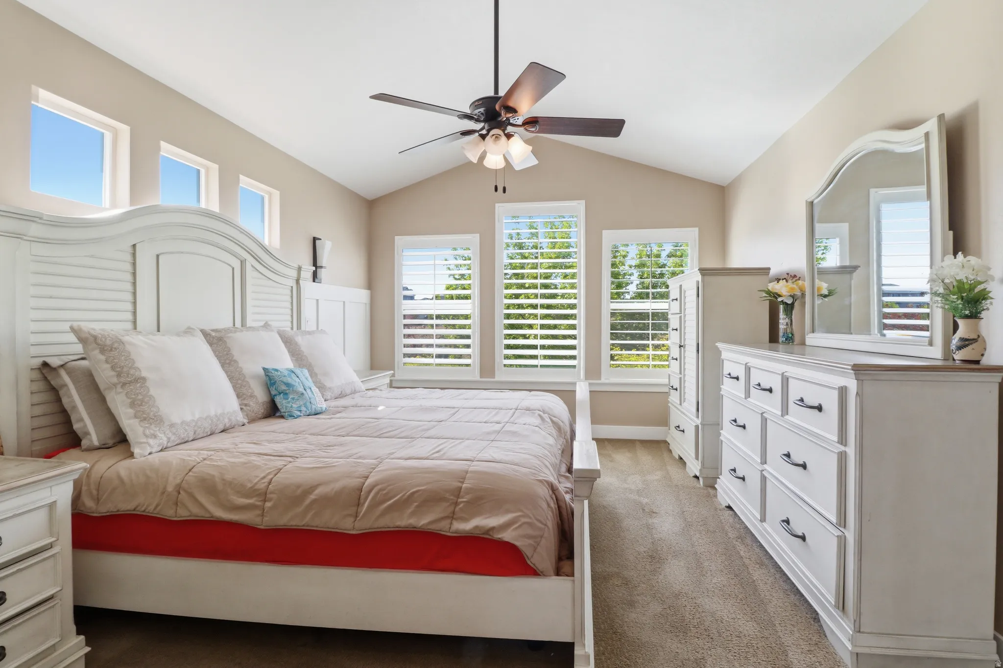 Carpeted master bedroom with lofted ceiling and a ceiling fan