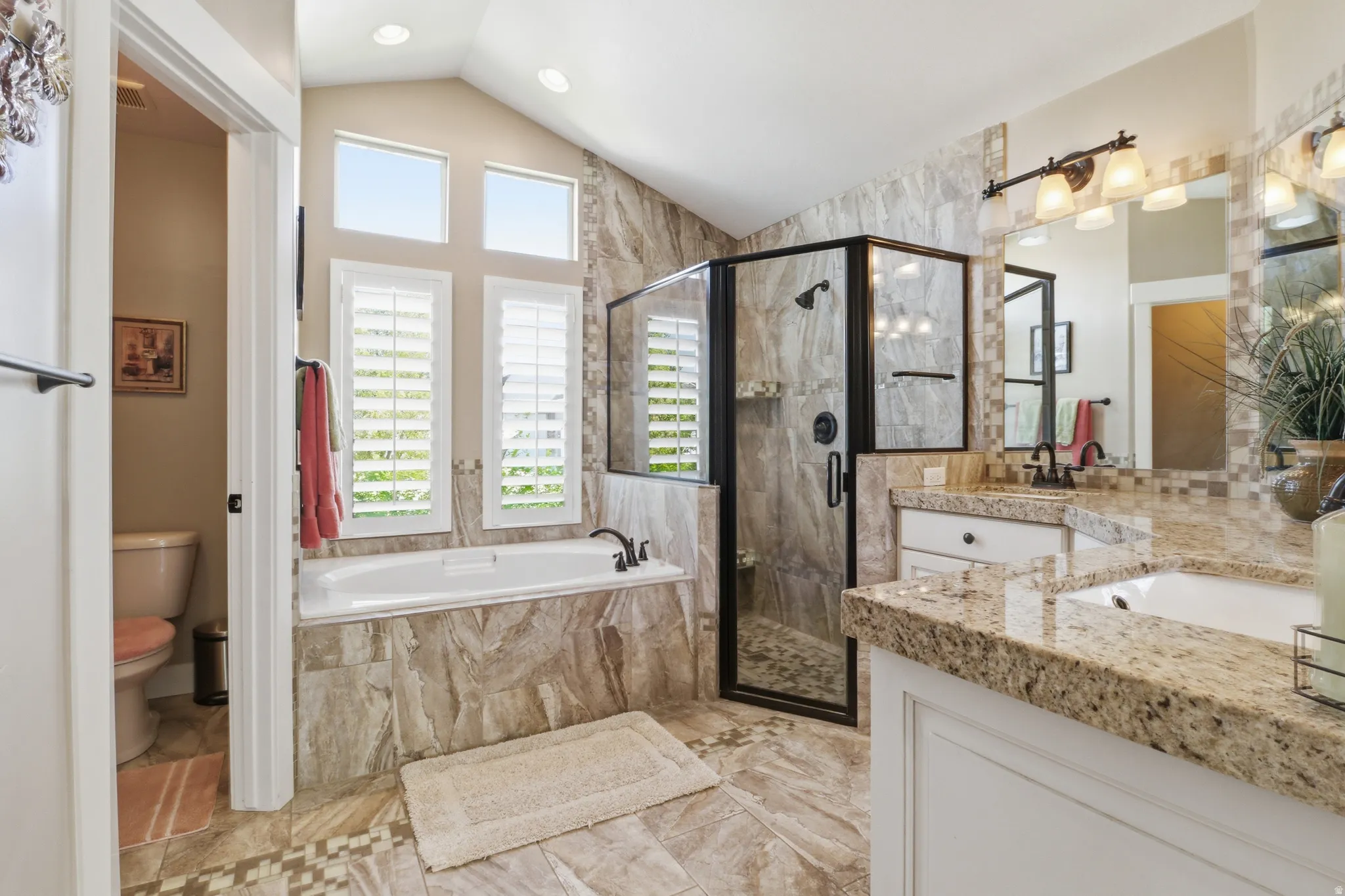 Full master bathroom featuring a stall shower, vanity, vaulted ceiling, a garden tub, and recessed lighting