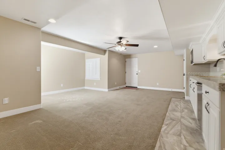 Unfurnished living room featuring ceiling fan, recessed lighting, and light carpet. Comes with wet bar and basement entrance, with multi-generational potential.