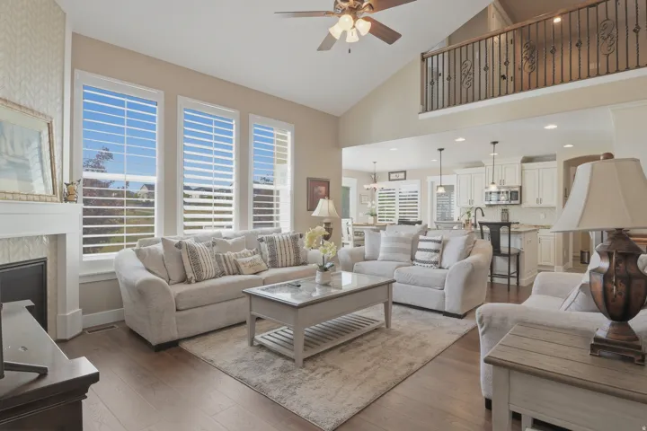Living room with ceiling fan, wood-type flooring, lofted ceiling, and a high end fireplace