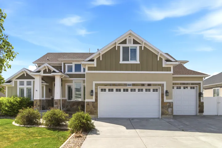 Craftsman-style house with driveway, stone siding, board and batten siding, and roof with shingles