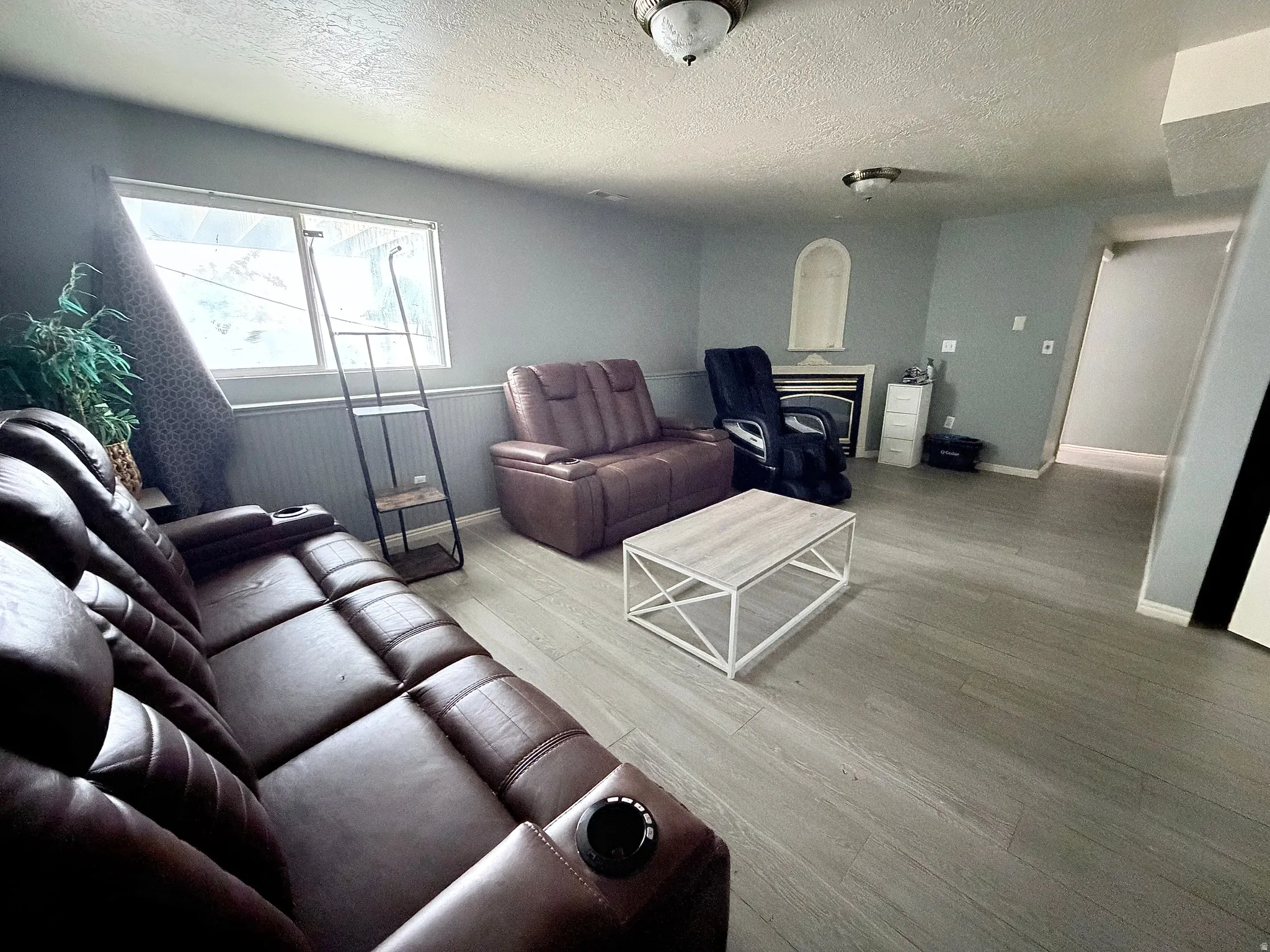 Living room with wood finished floors, a textured ceiling, and wainscoting