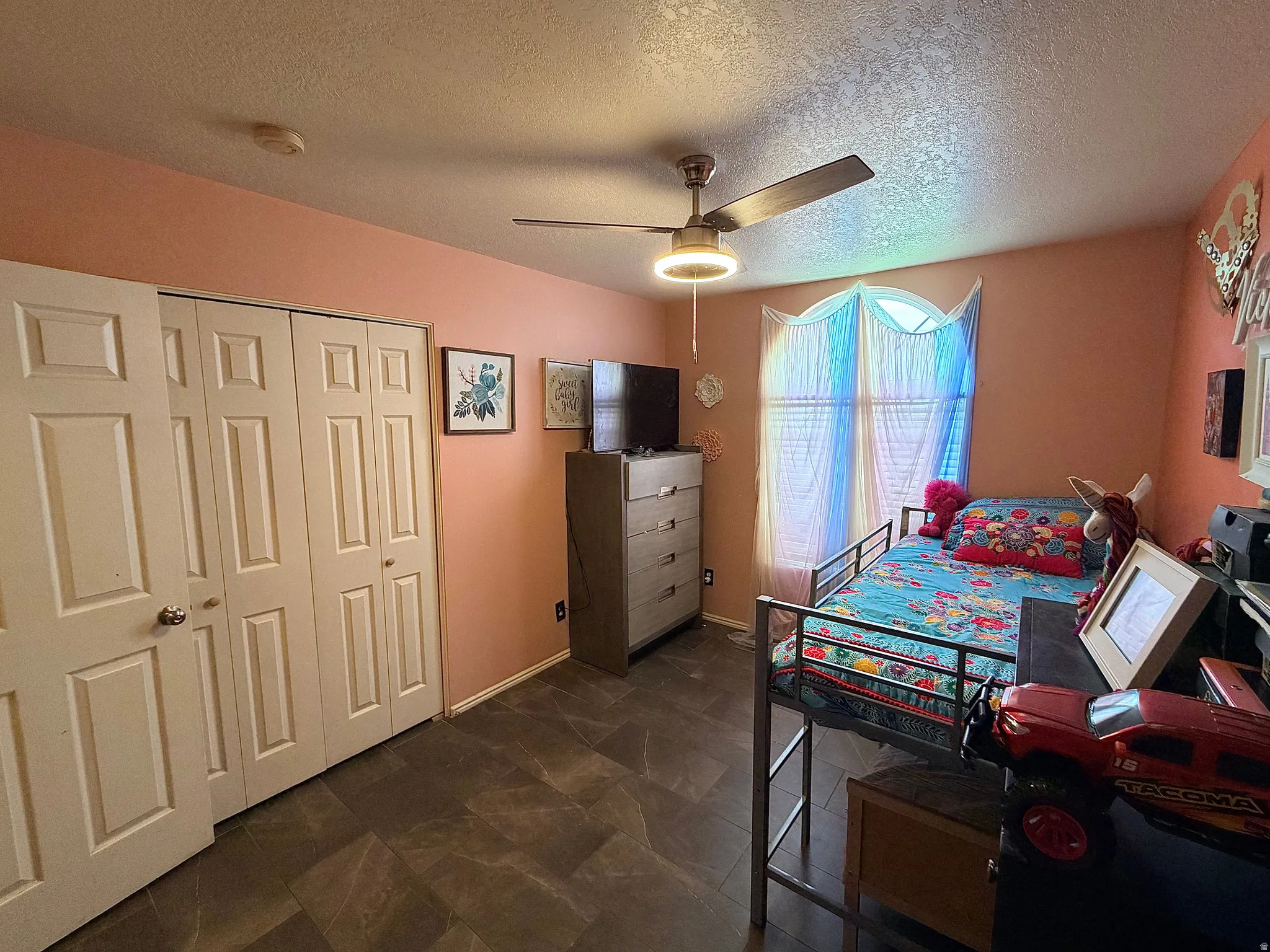 Bedroom with a closet, a ceiling fan, and a textured ceiling