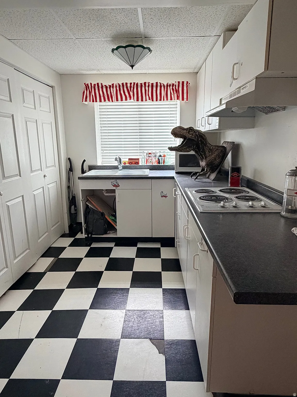 Kitchen with dark floors, dark countertops, electric stovetop, and a drop ceiling