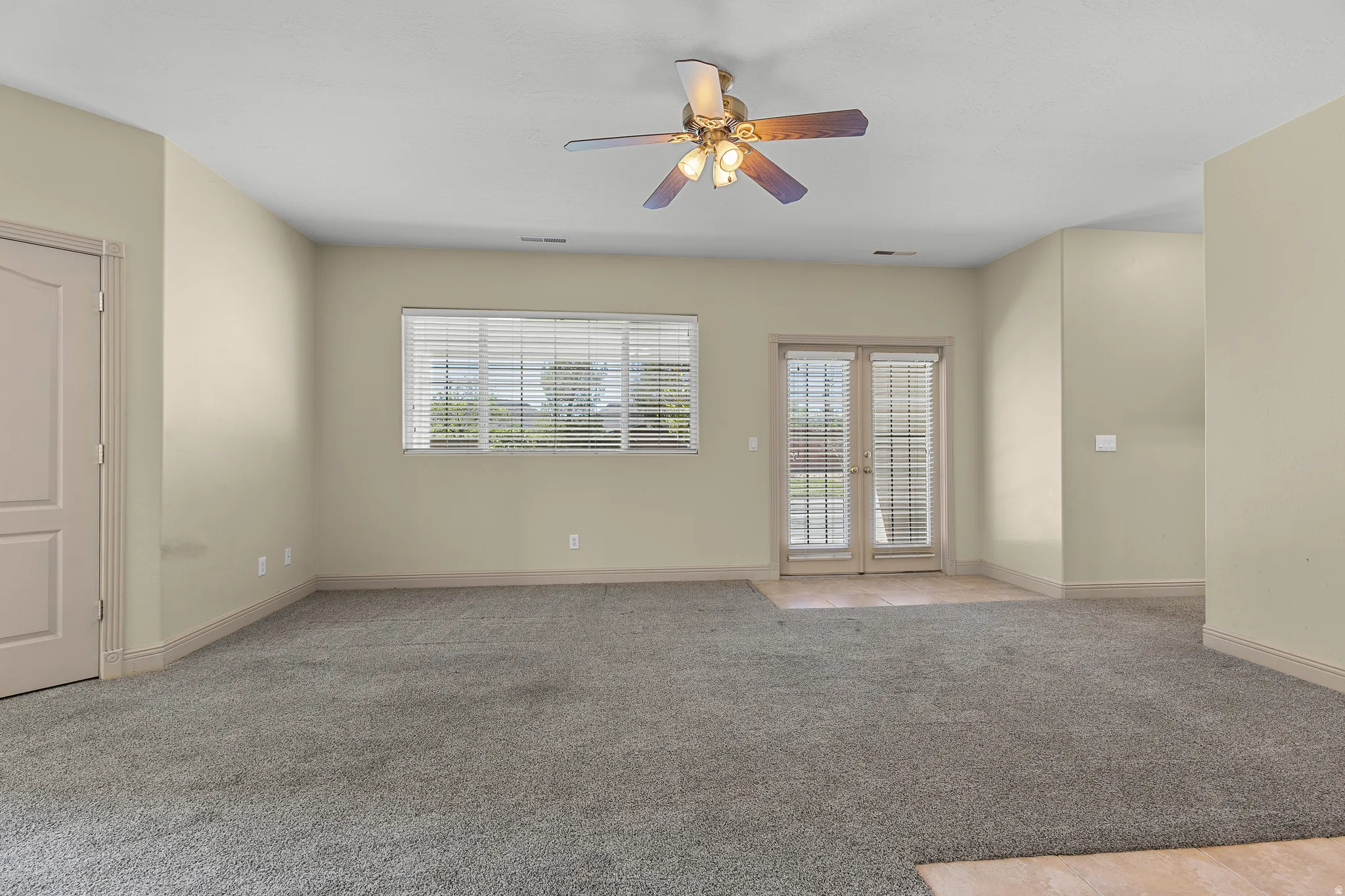 Unfurnished room featuring light carpet, ceiling fan, and french doors