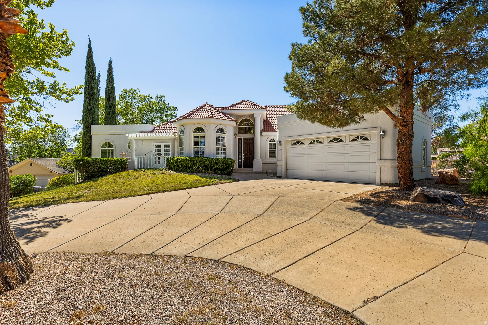 Mediterranean / spanish home with concrete driveway, stucco siding, an attached garage, and a tile roof