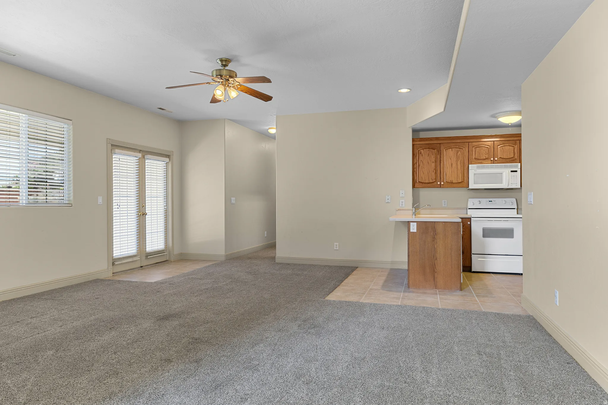 Kitchen featuring light countertops, open floor plan, white appliances, light colored carpet, and ceiling fan