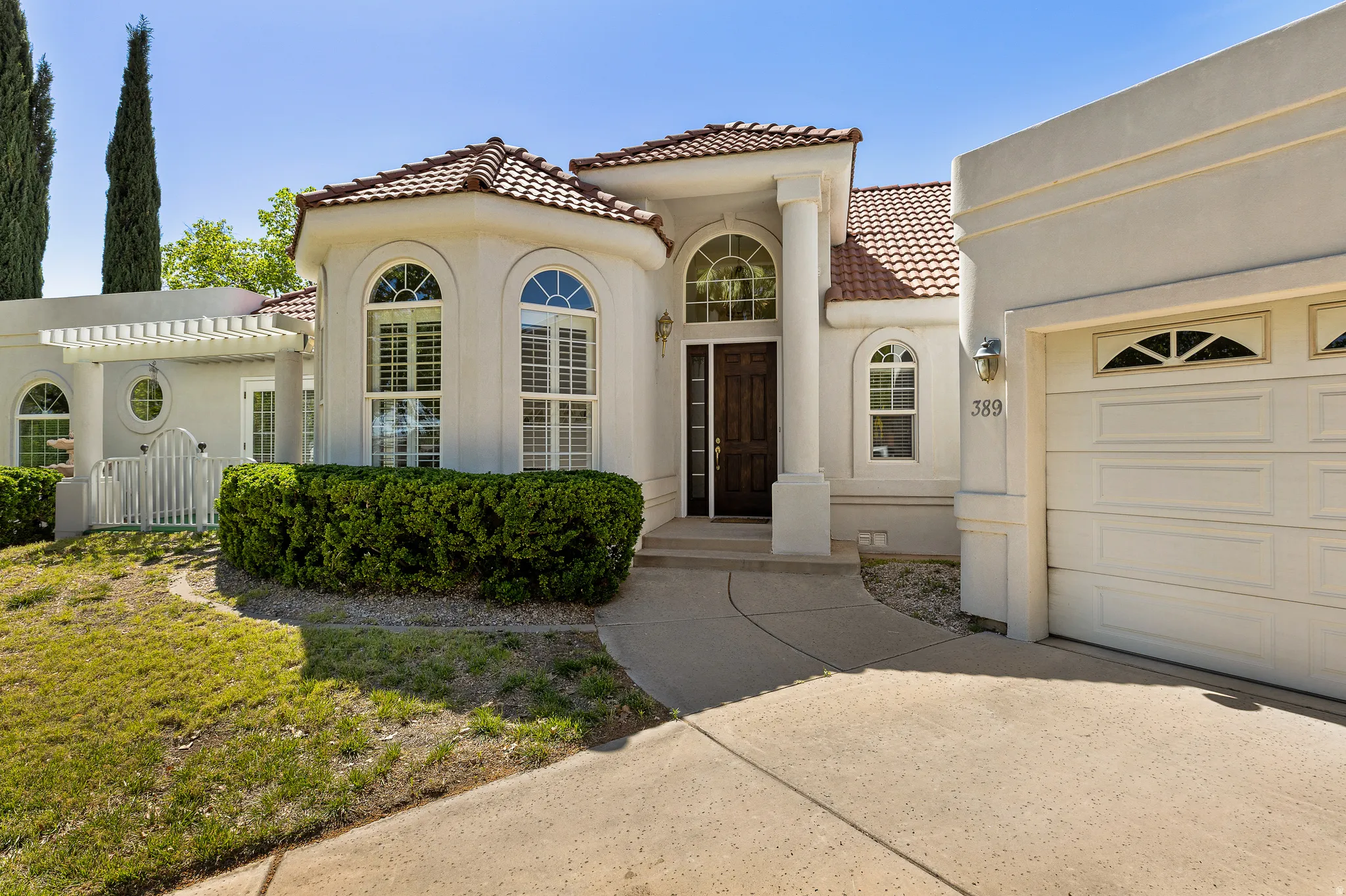 Mediterranean / spanish-style home with a tiled roof, stucco siding, an attached garage, and concrete driveway