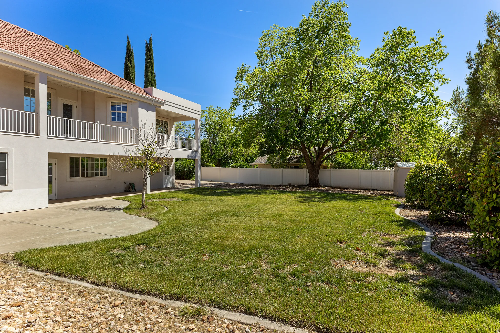 Fenced backyard with a patio and a balcony