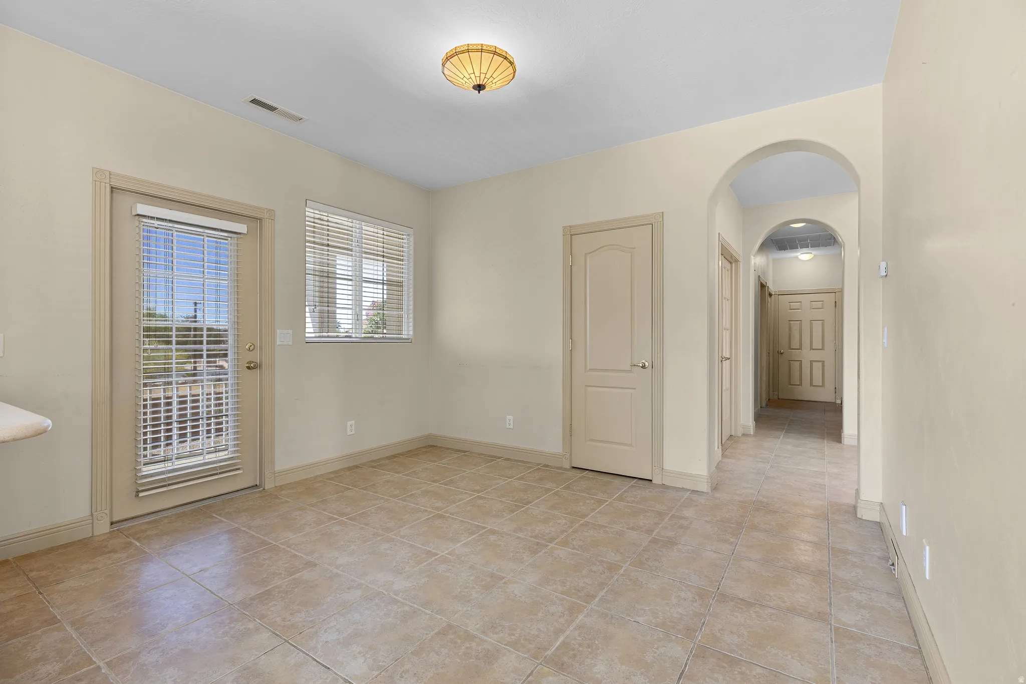 Spare room with arched walkways and light tile patterned flooring