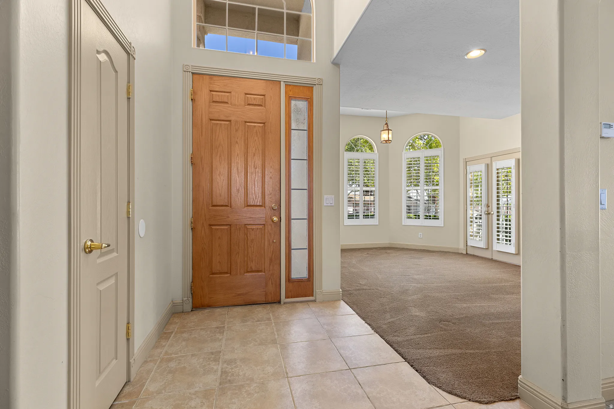 Entryway with light colored carpet, light tile patterned floors, french doors, recessed lighting, and a high ceiling