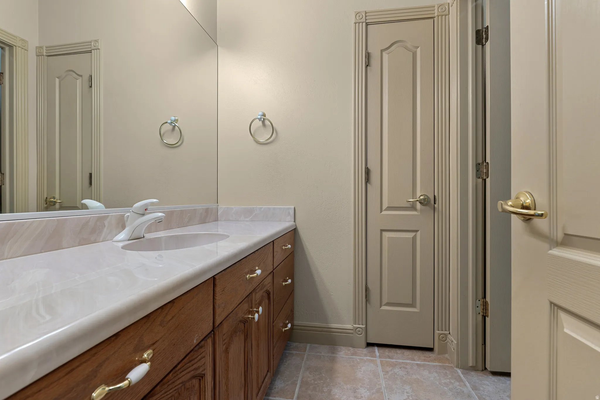 Bathroom with vanity, a closet, and light tile patterned flooring