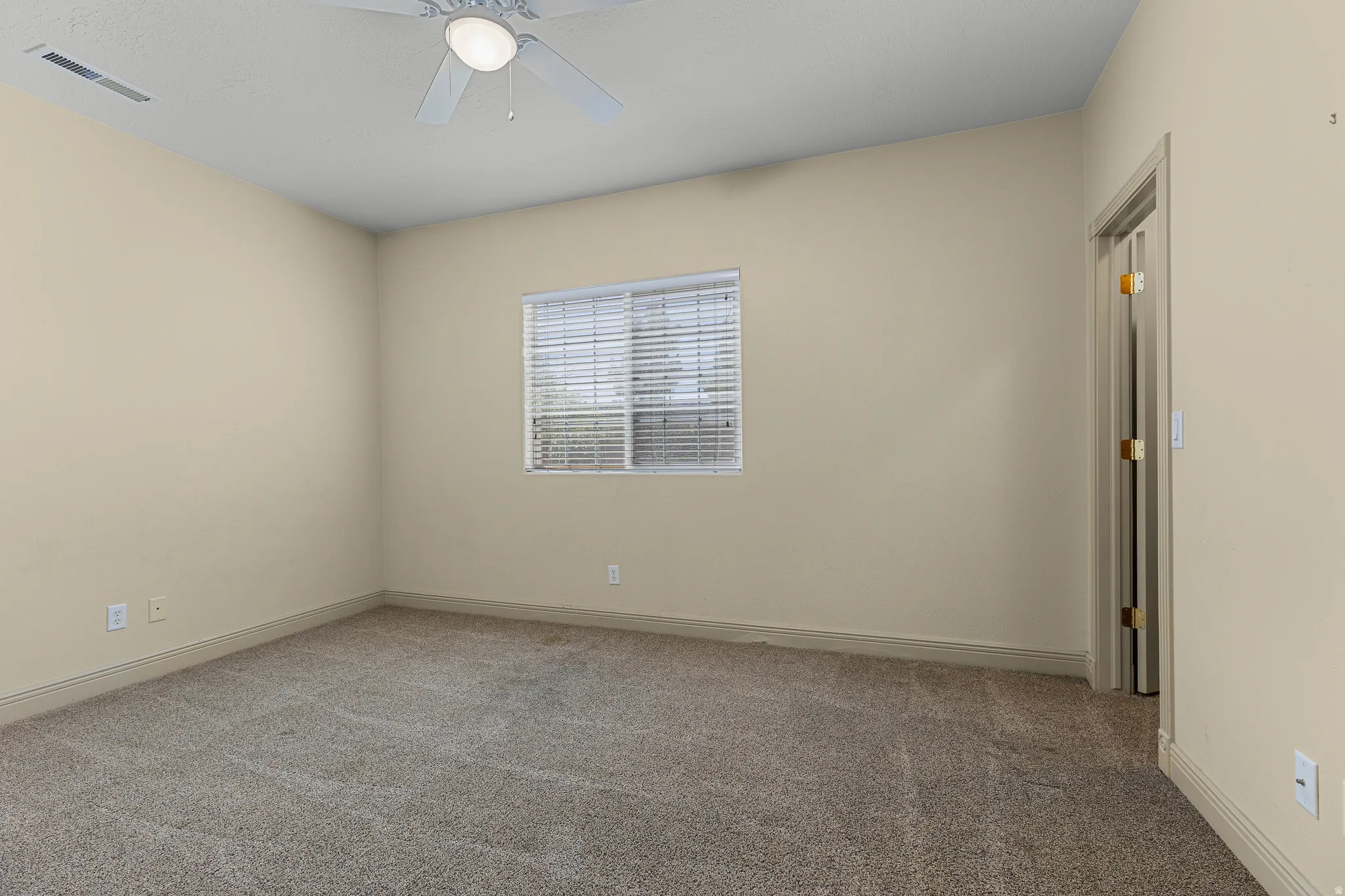 Carpeted empty room featuring ceiling fan and baseboards