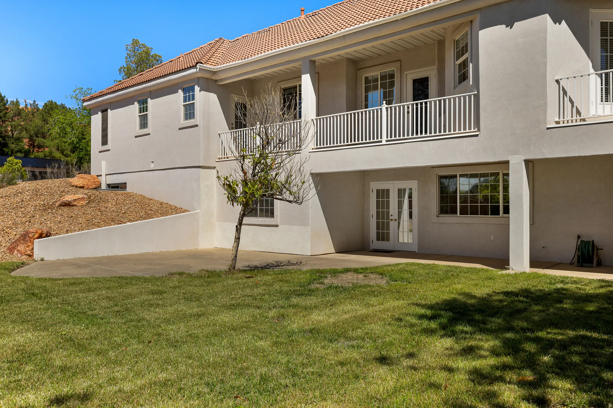 Back of house with french doors, stucco siding, a balcony, and a patio area