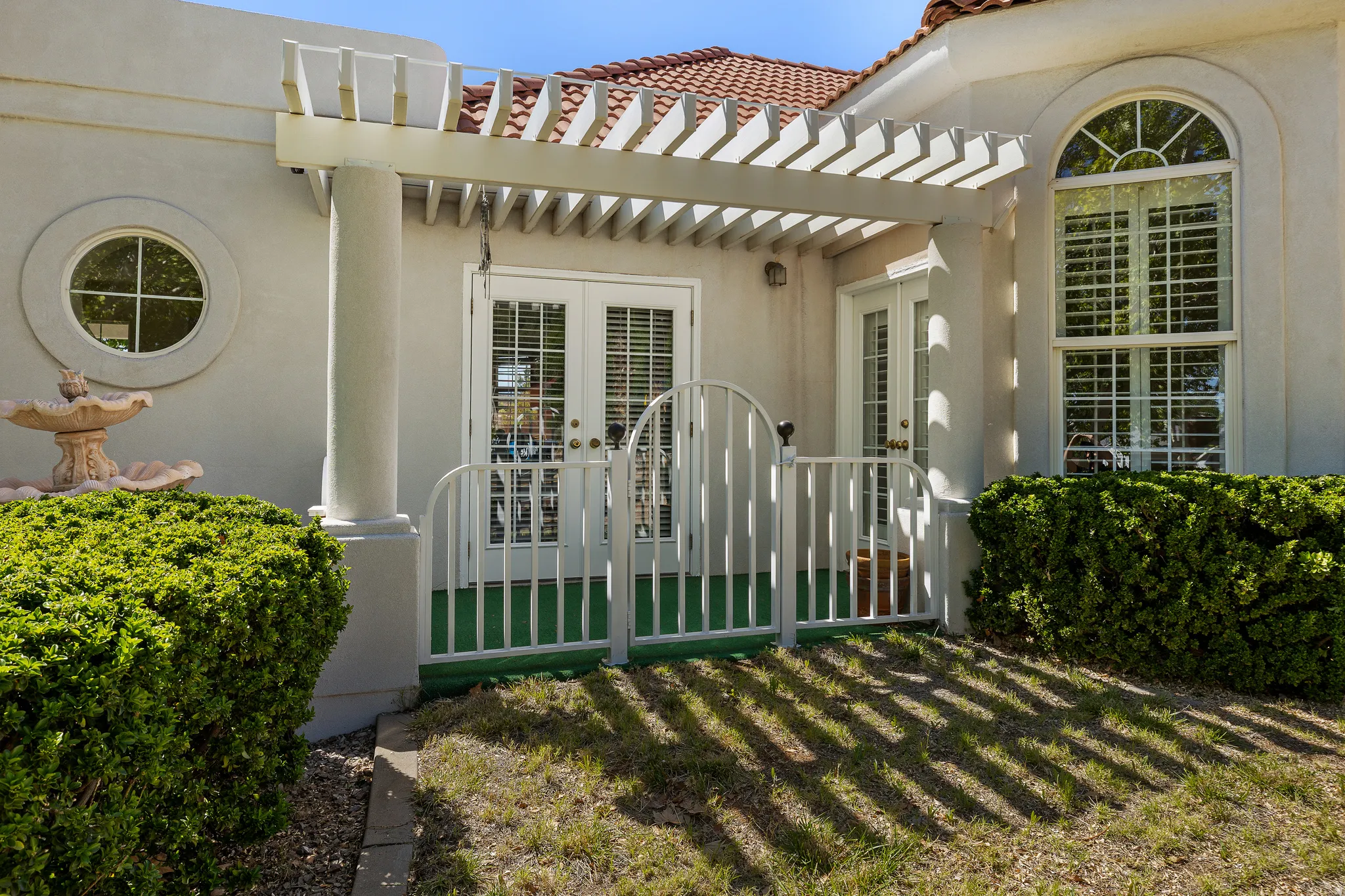 View of exterior entry with french doors, stucco siding, a tile roof, and a patio